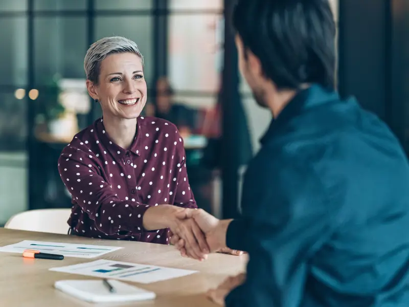 Smiling businesswoman greeting young businessman.