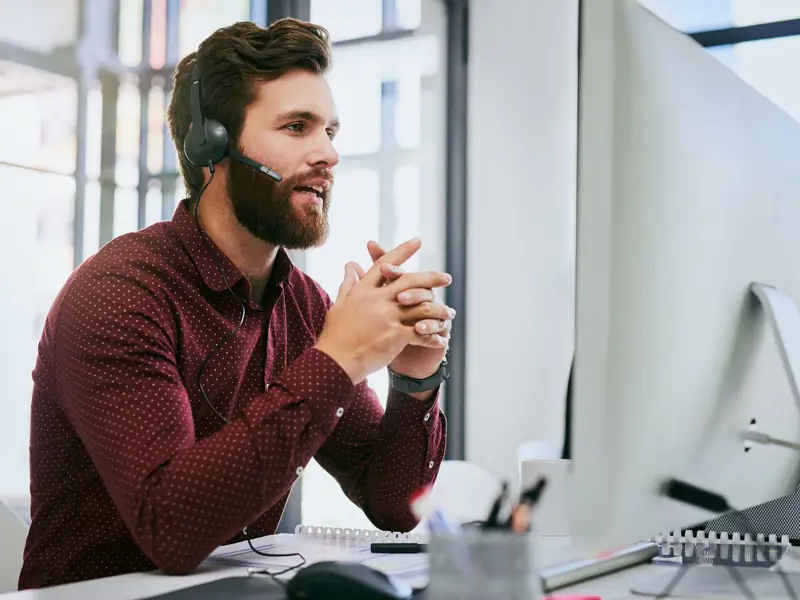 Businessman sitting at his desk talking on a headset.